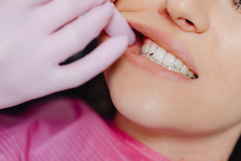 A dentist's gloved hand inspecting a patient's teeth during a check-up.