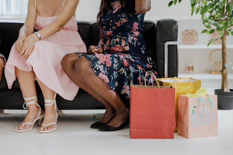 Women relaxing on a sofa with colorful shopping bags in a cozy indoor setting.